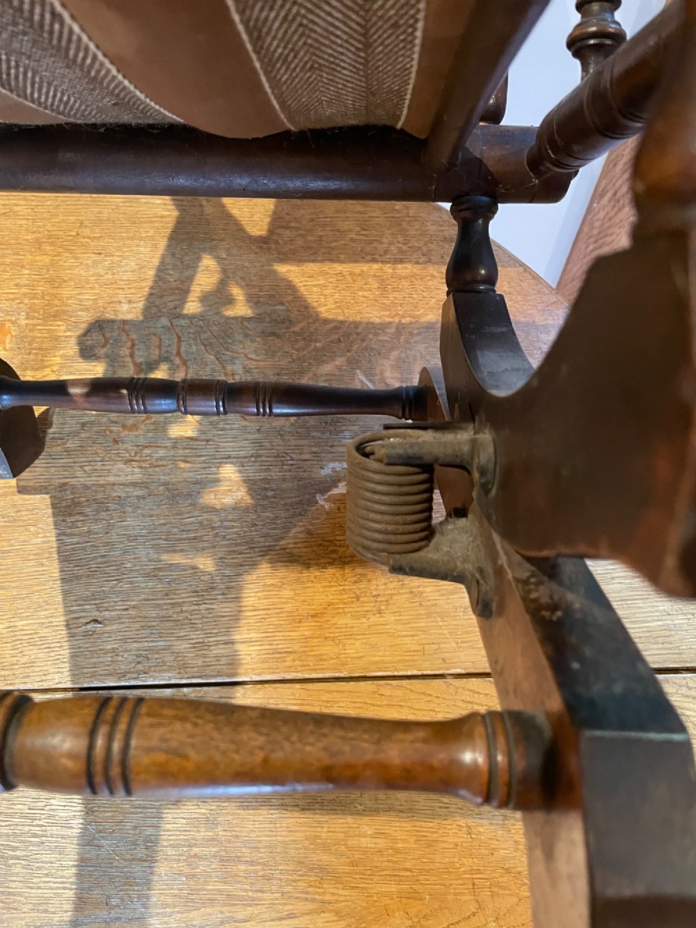 An antique American childs wooden platform rocking chair with turned spindles, tapestry upholstered panels, and stud details. View II