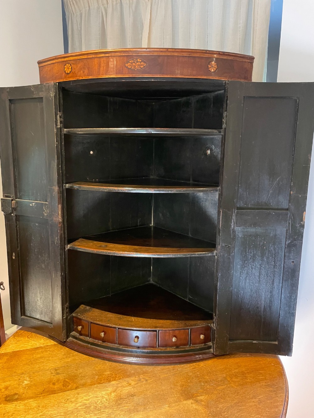 A Georgian mahogany bowfront corner cupboard featuring twin doors and inlaid marquetry motifs. View II