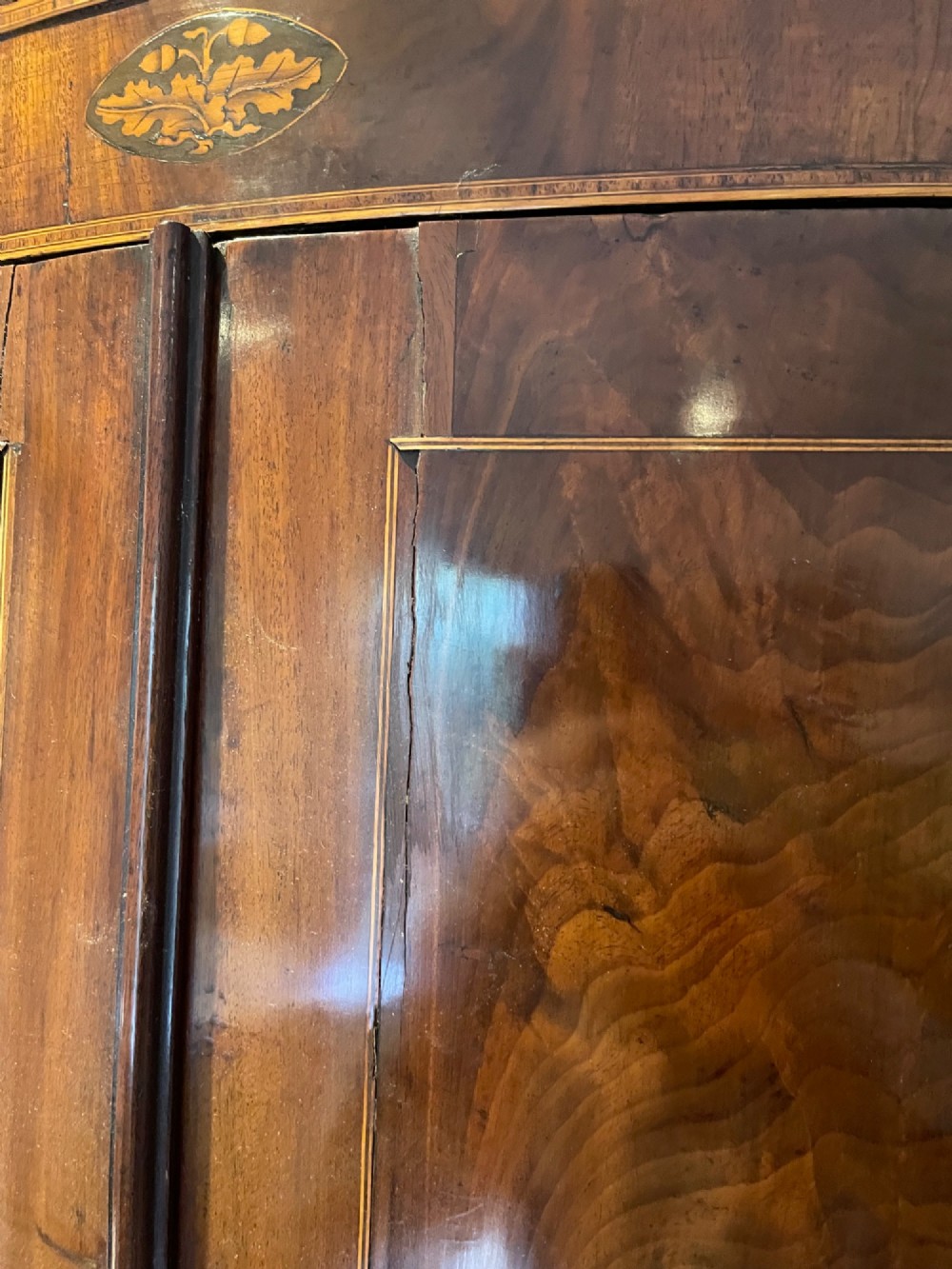 A Georgian mahogany bowfront corner cupboard featuring twin doors and inlaid marquetry motifs. View IV