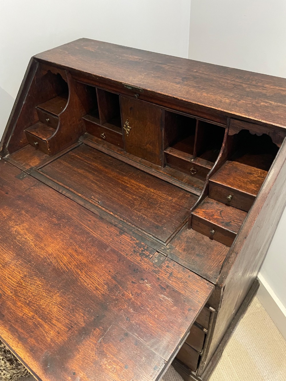 An 18th-century Queen Anne dark oak bureau featuring a slanted fall-front writing flap over drawers with brass drop handles. View II