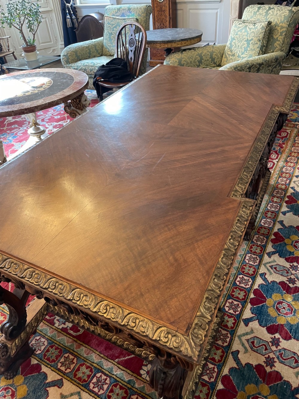 A hand-carved dark walnut Italian desk featuring a rectangular top, carved frieze apron, and ornate trestle legs with figural supports and paw feet. View IV