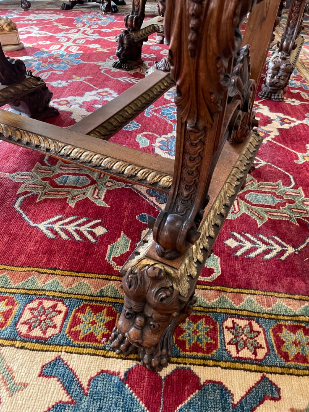 A hand-carved dark walnut Italian desk featuring a rectangular top, carved frieze apron, and ornate trestle legs with figural supports and paw feet. View V