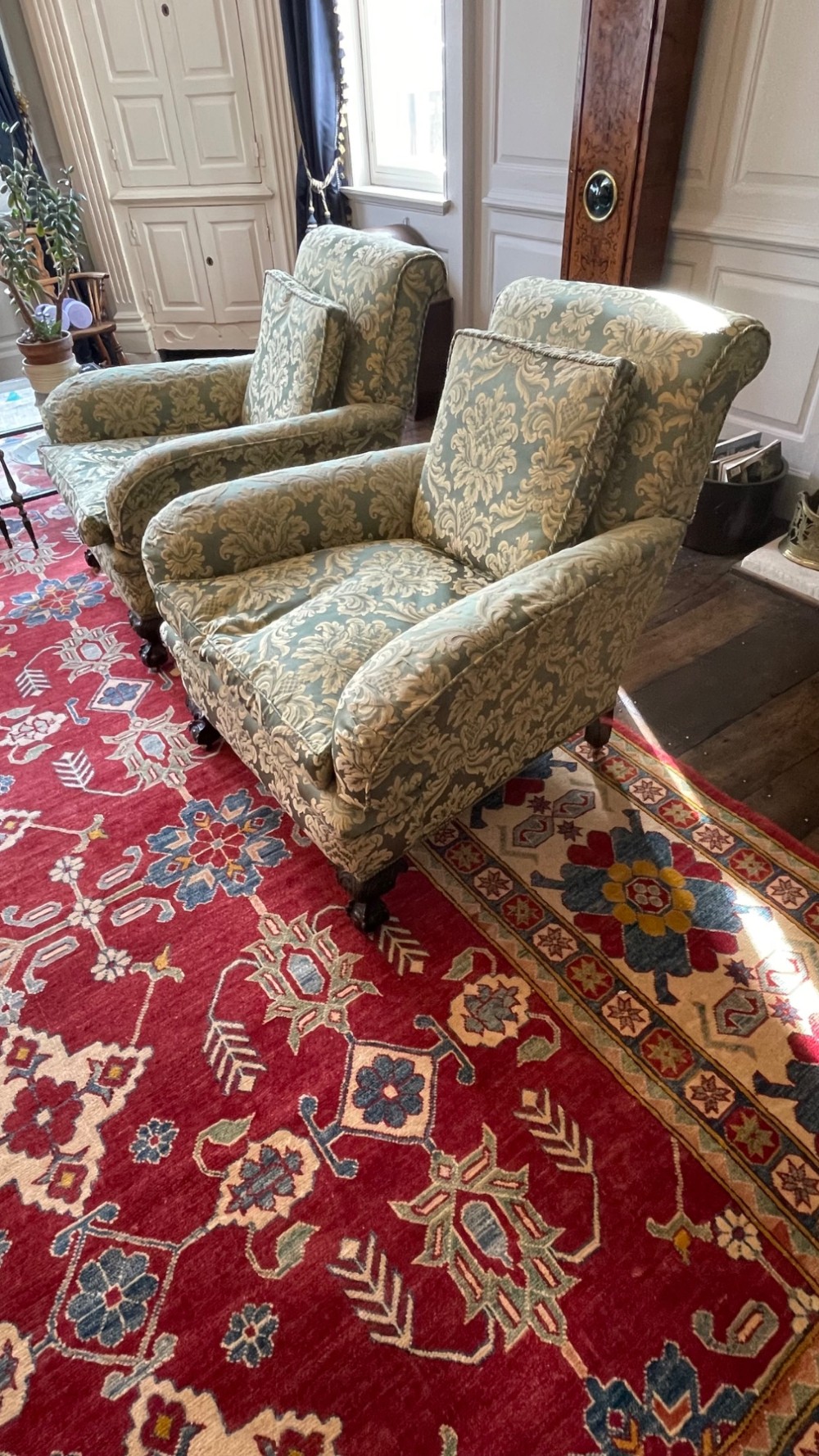 A matching pair of fully upholstered armchairs covered in pale blue and cream floral damask fabric with dark turned wooden legs. View II