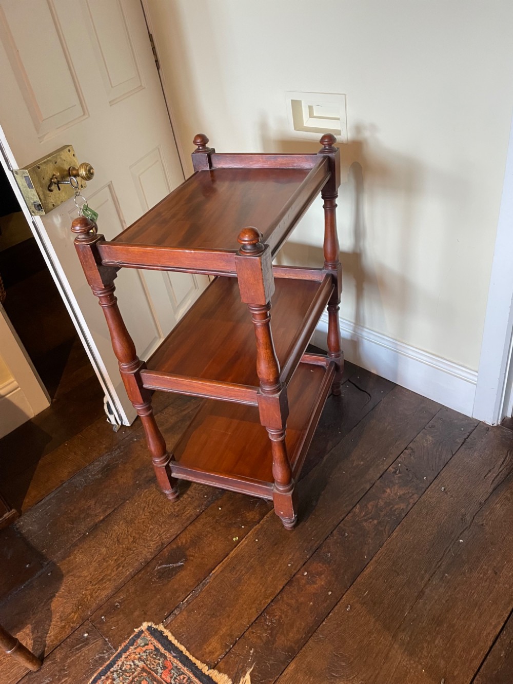 A three-tiered mahogany dumb waiter featuring turned support columns, corner finials, and raised galleries around the shelves. View II