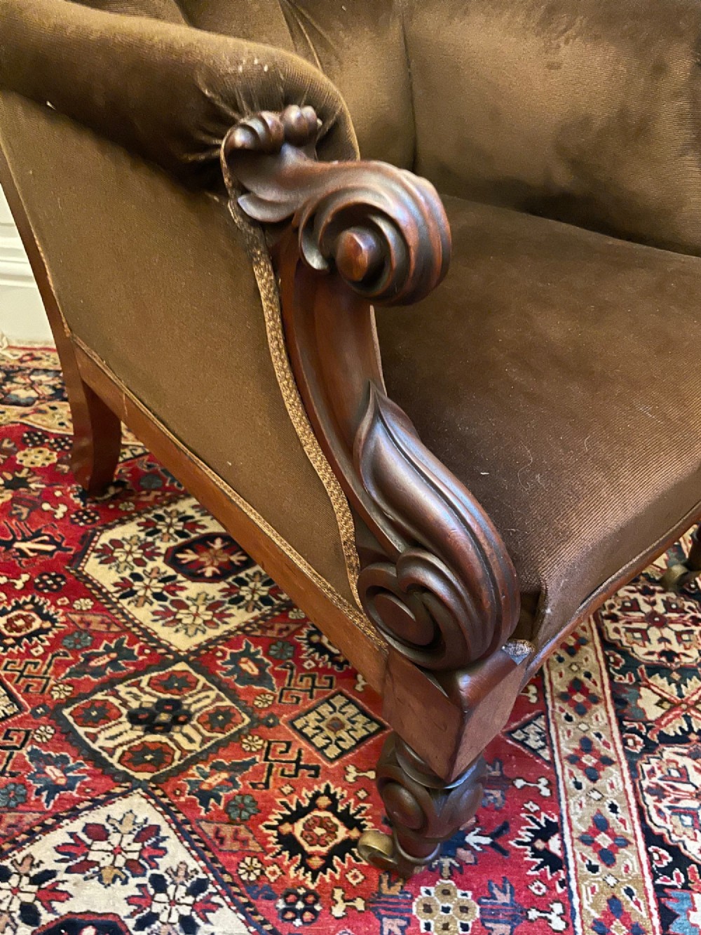 A Victorian mahogany library chair featuring dark brown velvet button-tufted upholstery, carved scroll arms, and brass castors. View III