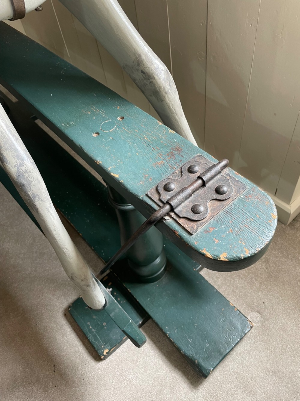 A large antique carved wooden dapple grey rocking horse with leather tack mounted on a dark green safety glider stand. View II