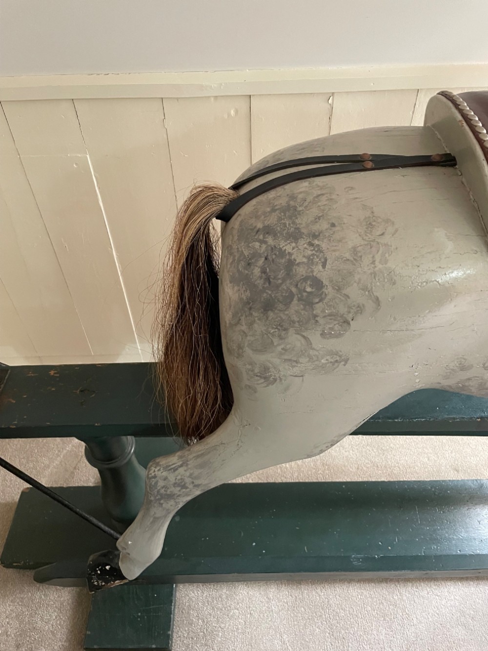A large antique carved wooden dapple grey rocking horse with leather tack mounted on a dark green safety glider stand. View IV