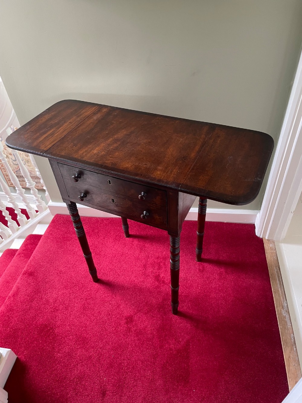A dark mahogany drop-leaf side table featuring two drawers with wooden knobs and four slender turned legs. View II