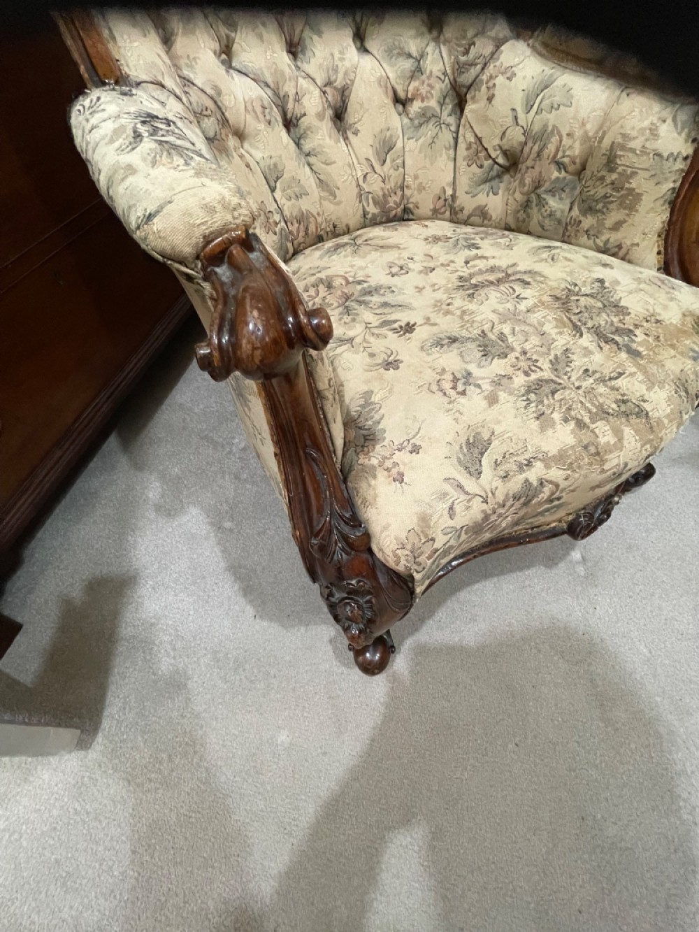 A Victorian carved walnut armchair featuring button-tufted floral fabric upholstery, curved armrests, and cabriole legs on brass castors. View III