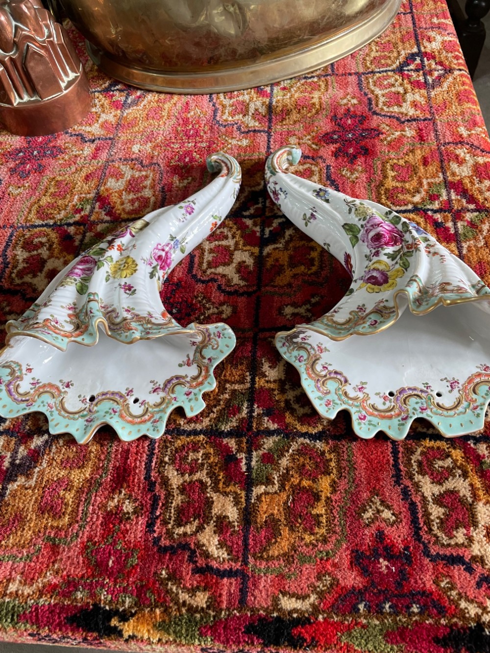 A pair of curved porcelain cornucopia wall vases with hand-painted floral sprays, light blue fluted rims, and gilded scroll accents. View II