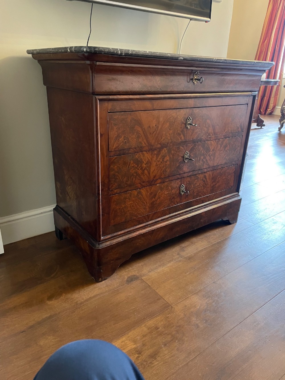 A 19th-century French Louis Philippe mahogany chest of drawers with a dark marble top, pull-out brushing slide, and brass keyhole escutcheons.