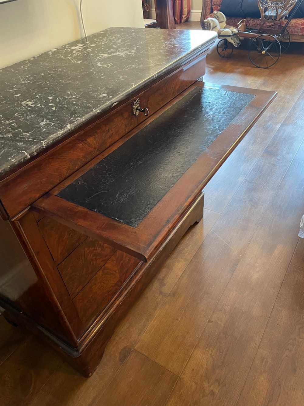A 19th-century French Louis Philippe mahogany chest of drawers with a dark marble top, pull-out brushing slide, and brass keyhole escutcheons. View III