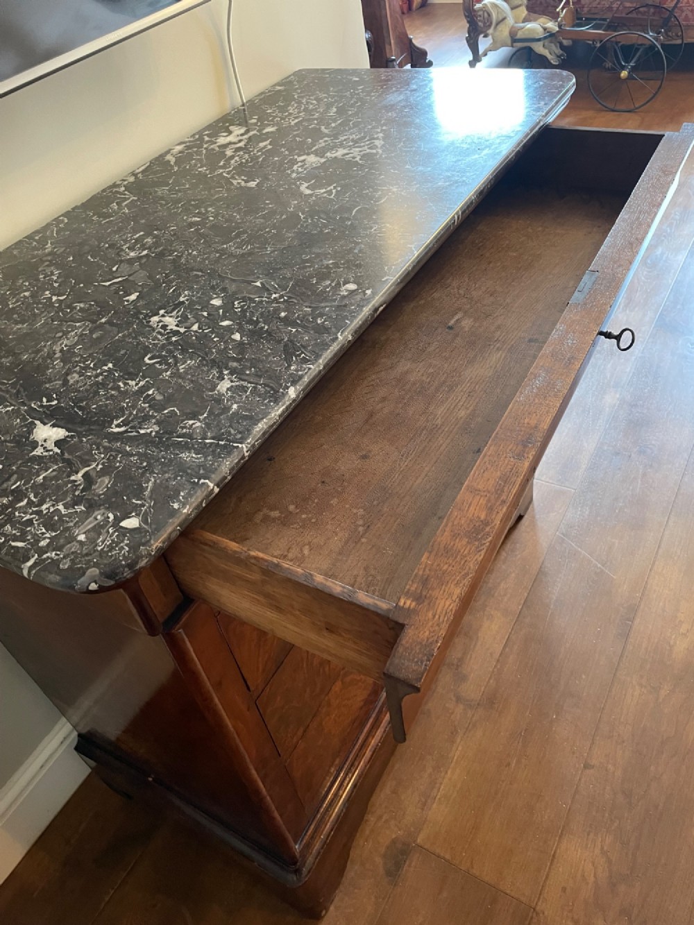 A 19th-century French Louis Philippe mahogany chest of drawers with a dark marble top, pull-out brushing slide, and brass keyhole escutcheons. View V