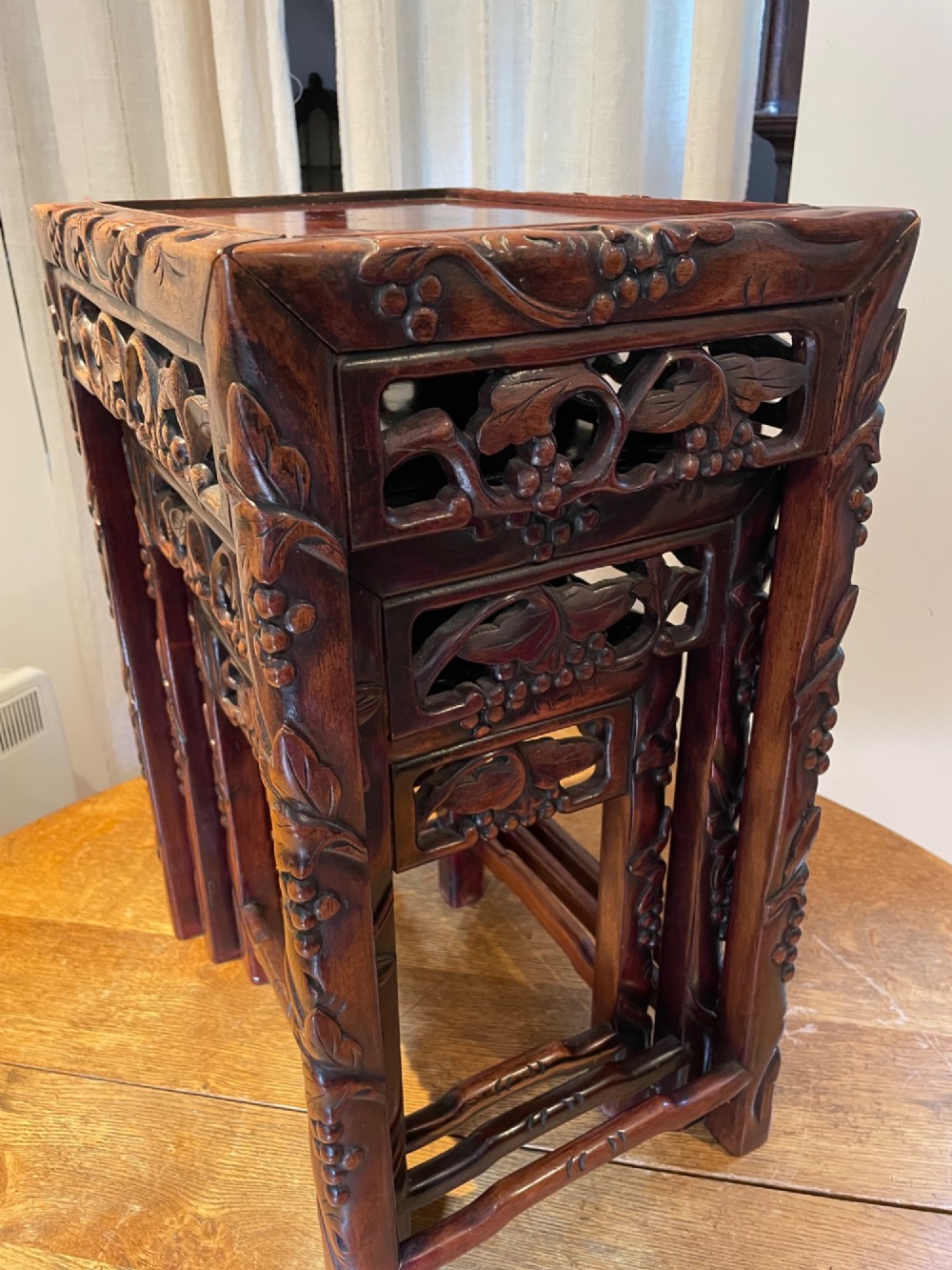 A top-down view of a set of three dark hardwood Chinese nesting tables featuring relief-carved decorative borders. View II
