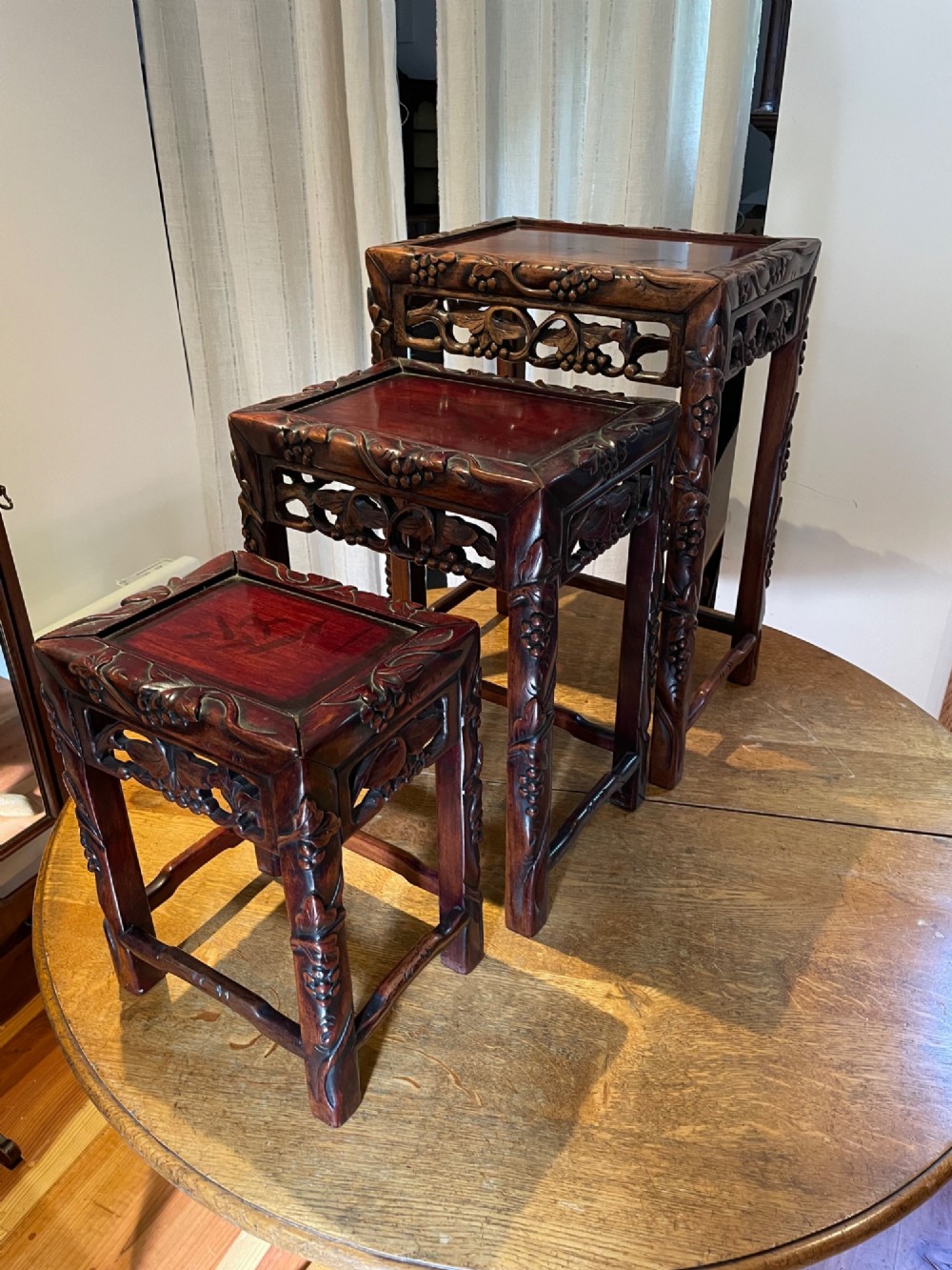 A top-down view of a set of three dark hardwood Chinese nesting tables featuring relief-carved decorative borders. View III