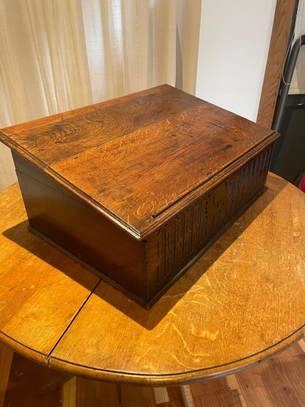 A rectangular warm brown oak bible box featuring a slanted hinged lid, carved vertical details on the front panel, and a central brass lock plate. View II