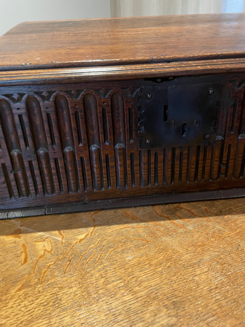 A rectangular warm brown oak bible box featuring a slanted hinged lid, carved vertical details on the front panel, and a central brass lock plate. View III