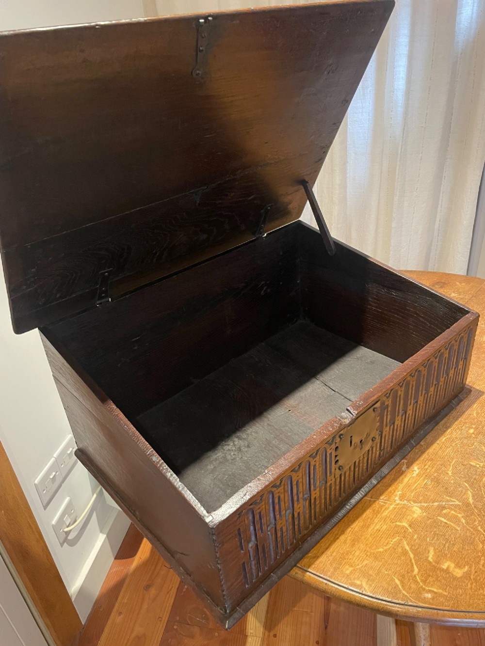 A rectangular warm brown oak bible box featuring a slanted hinged lid, carved vertical details on the front panel, and a central brass lock plate. View IV