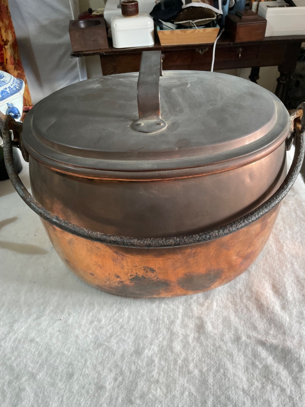 A large antique copper pot featuring a fitted lid with a copper handle and an arched iron swing handle. View II