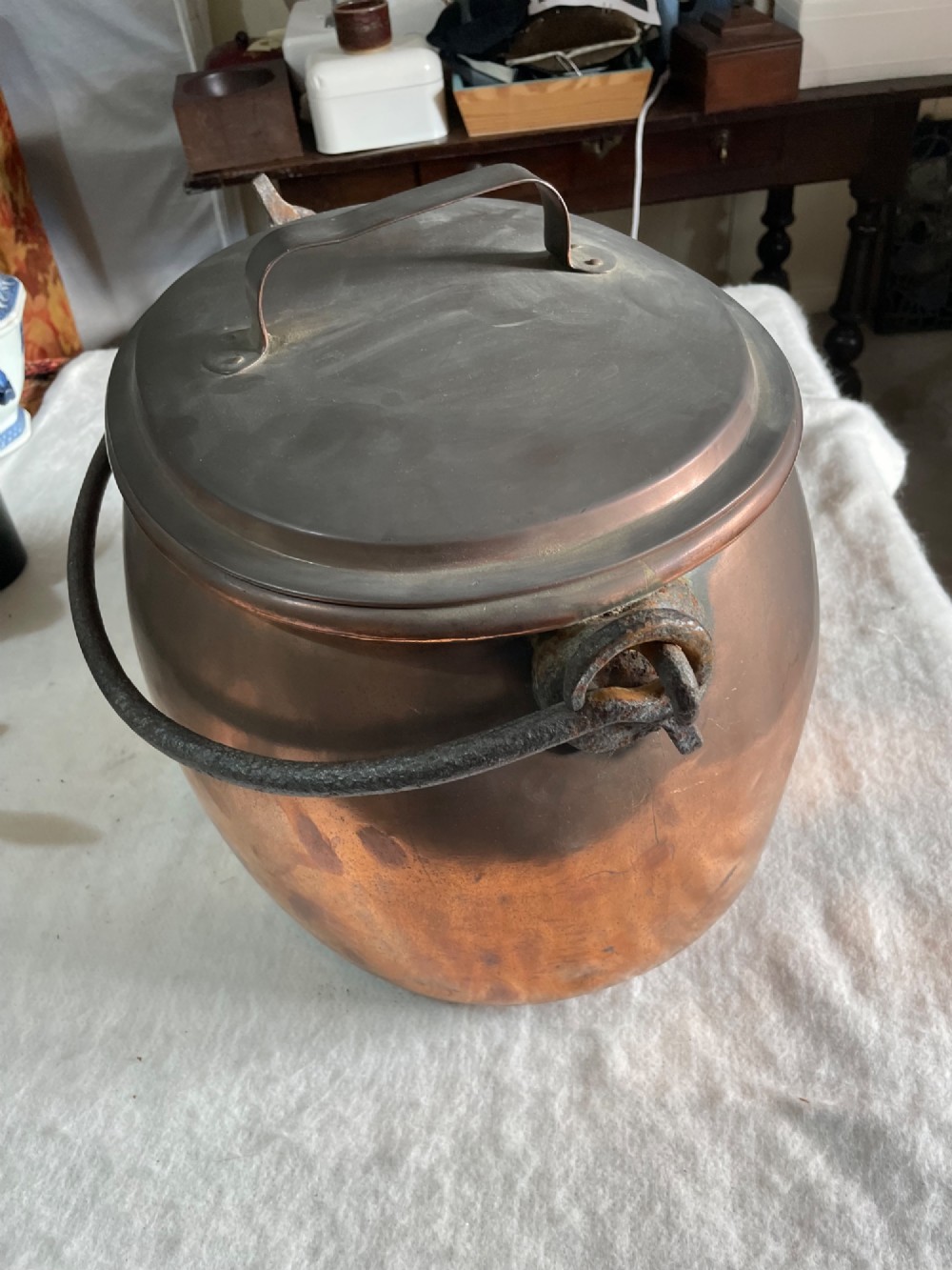 A large antique copper pot featuring a fitted lid with a copper handle and an arched iron swing handle. View III