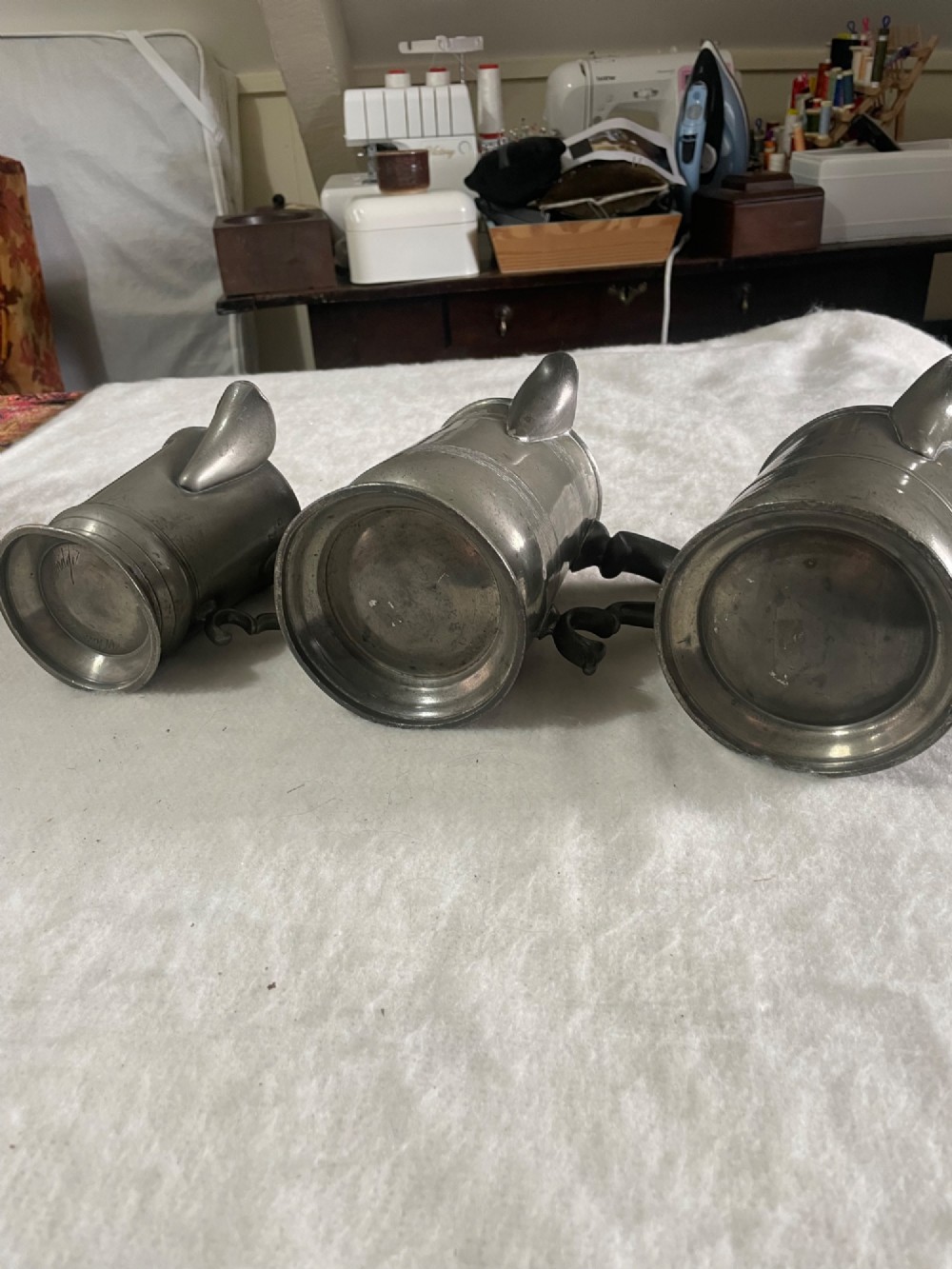 A set of three antique pewter measures of varying sizes, each featuring a poured spout, double scroll handle, and stamped touchmarks. View II