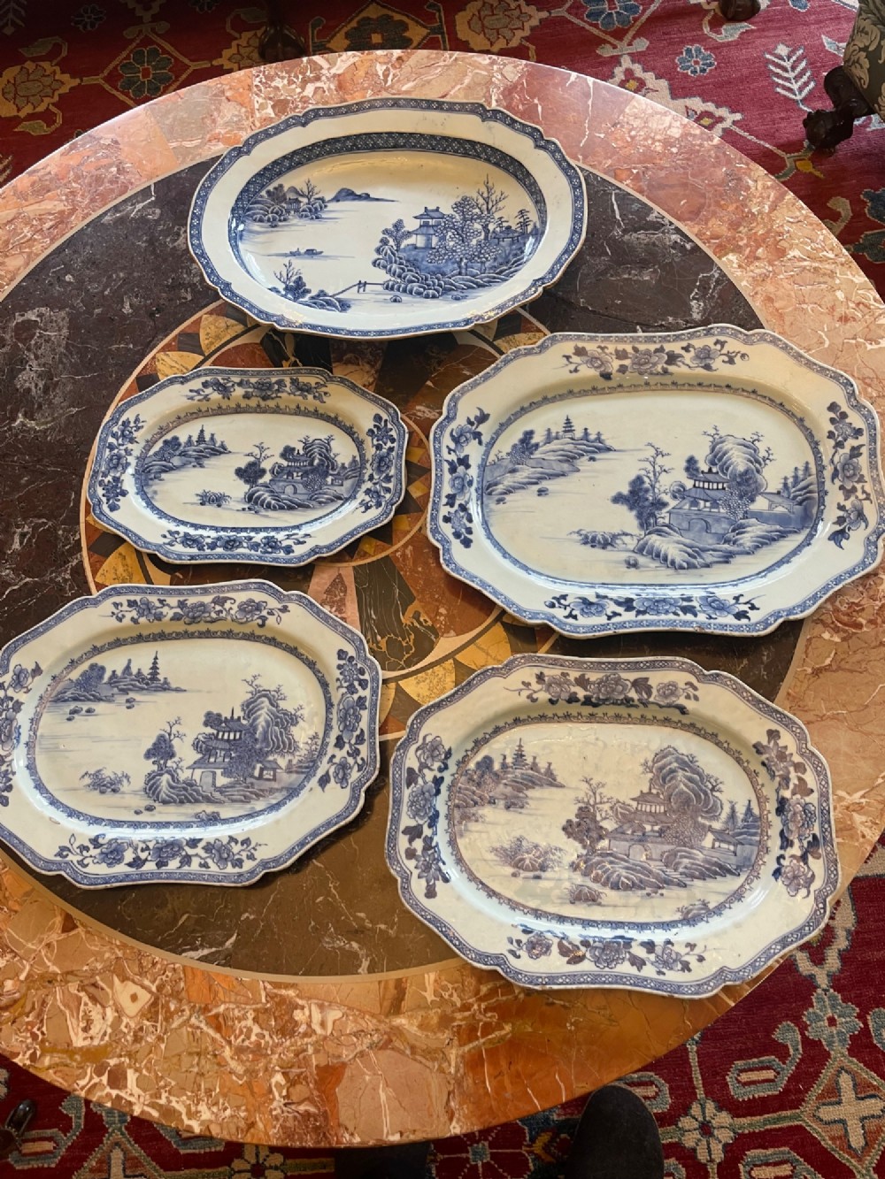 A set of five antique blue and white Chinese export porcelain oval platters with scalloped rims, featuring hand-painted landscape scenes.