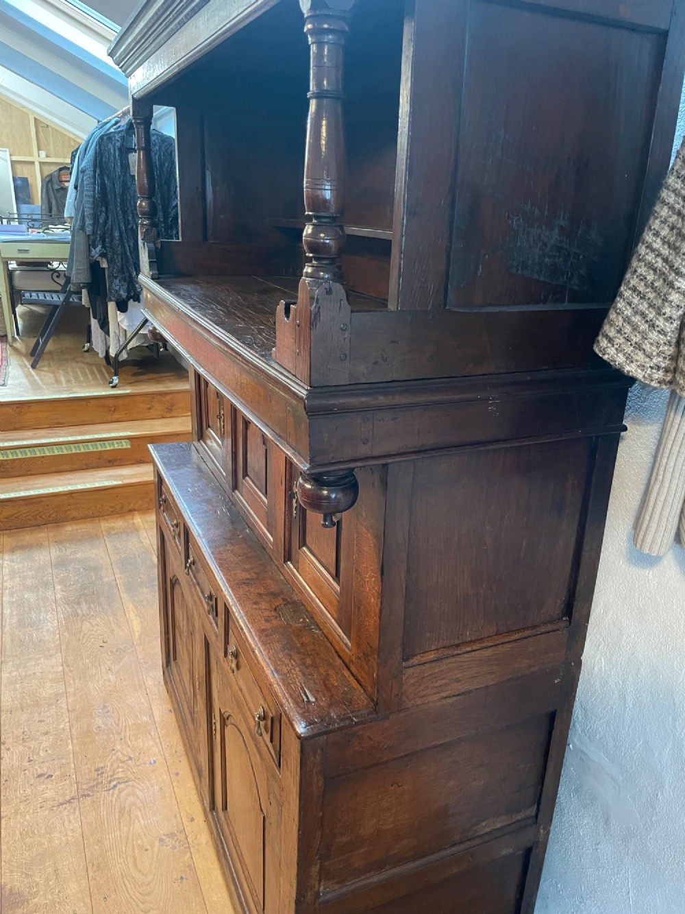 A dark oak three-tier Welsh tridarn featuring an open upper shelf with turned columns above a double-cupboard section and a lower base with drawers and doors. View IV