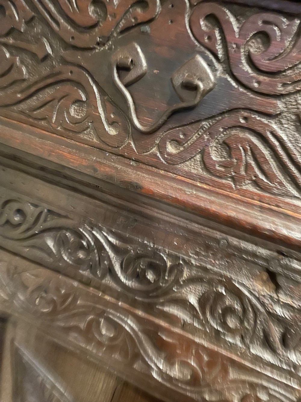 A dark carved oak court cupboard featuring an open upper shelf supported by turned balusters above two carved drawers and two panelled cupboard doors. View V