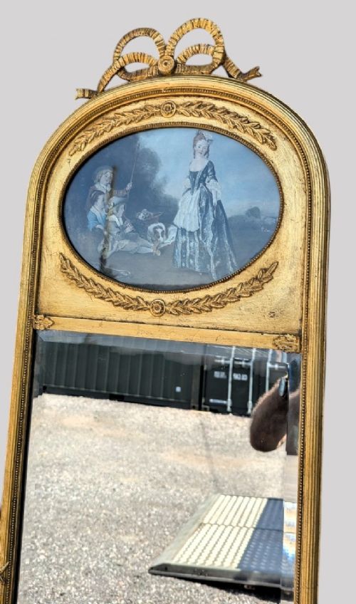 An arched giltwood pier mirror featuring a ribbon bow crest and an upper oval painted scene framed by laurel wreaths above a glass plate. View V