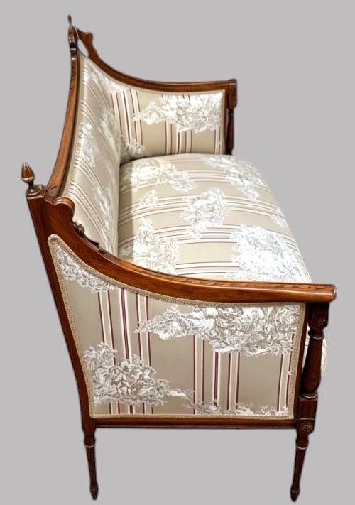 fig 1. An Edwardian walnut drawing room sofa featuring a sweeping curved backrest, turned front supports, slender tapered legs, and cream striped patterned upholstery.