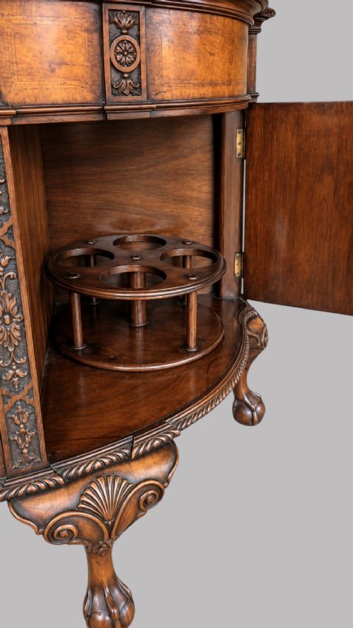 A bow-front burr walnut sideboard with carved pilasters, twin cupboard doors, a top drawer, and four carved cabriole legs ending in ball and claw feet. View IX
