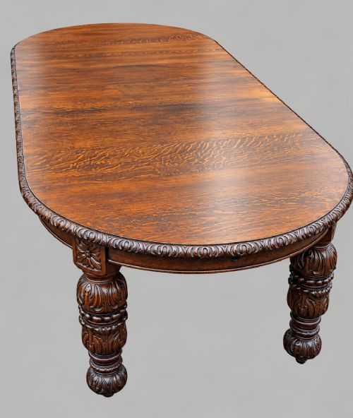 A late 19th-century oak extending dining table featuring a quarter-sawn wood top, carved apron moulding, and turned legs. View VI