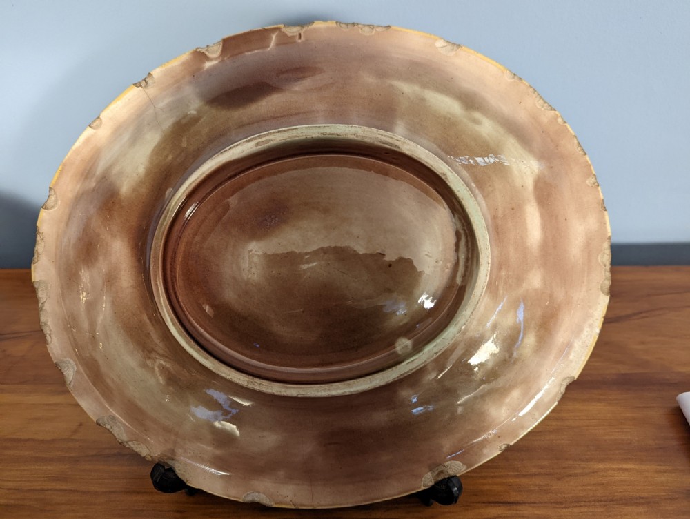 An oval Victorian majolica decorative ceramic dish featuring relief foliage, cobalt cabochons, and mottled green and brown lead glazing. View III