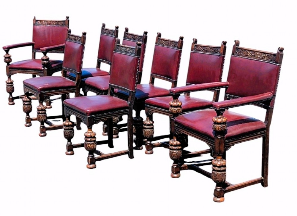 Set of eight dark oak dining chairs with carved top rails, turned legs, and burgundy leather upholstery secured with brass studs. View II