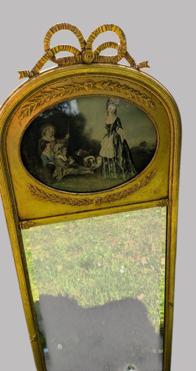An arched giltwood pier mirror featuring a ribbon bow crest and an upper oval painted scene framed by laurel wreaths above a glass plate. View X