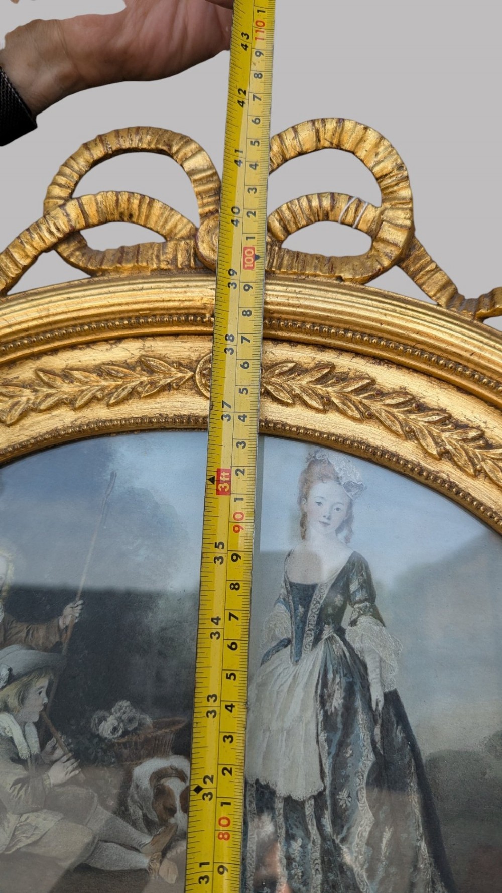 An arched giltwood pier mirror featuring a ribbon bow crest and an upper oval painted scene framed by laurel wreaths above a glass plate. View XII