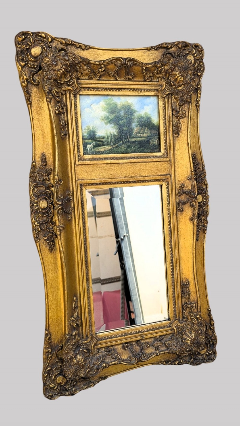 An elongated vertical giltwood pier mirror featuring an upper painted landscape panel above a rectangular glass mirror, set within a carved rococo-style frame. View III