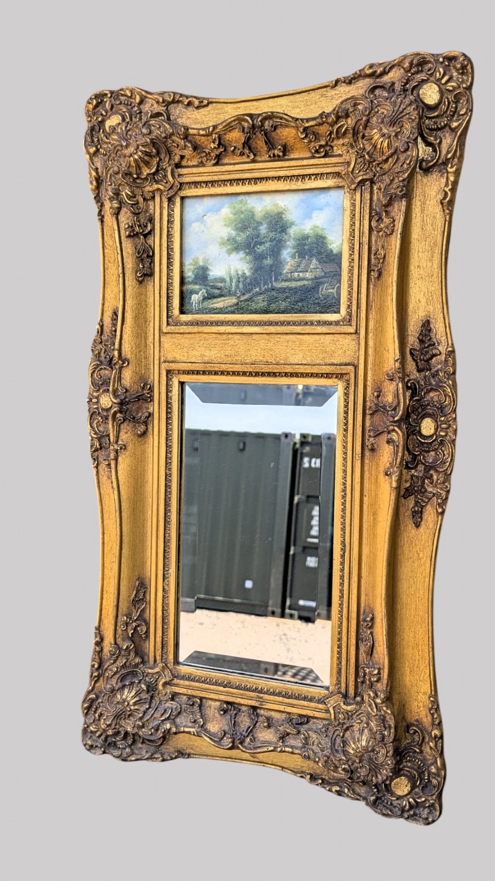 An elongated vertical giltwood pier mirror featuring an upper painted landscape panel above a rectangular glass mirror, set within a carved rococo-style frame. View IV