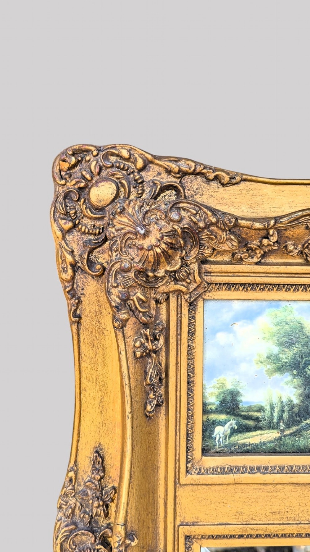 An elongated vertical giltwood pier mirror featuring an upper painted landscape panel above a rectangular glass mirror, set within a carved rococo-style frame. View VIII