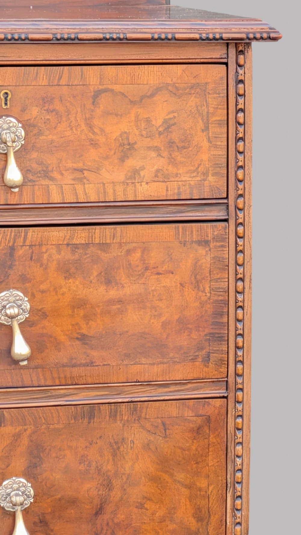 A Queen Anne style burr walnut chest of drawers featuring two short over two long drawers, brass drop handles, and carved cabriole legs. View III
