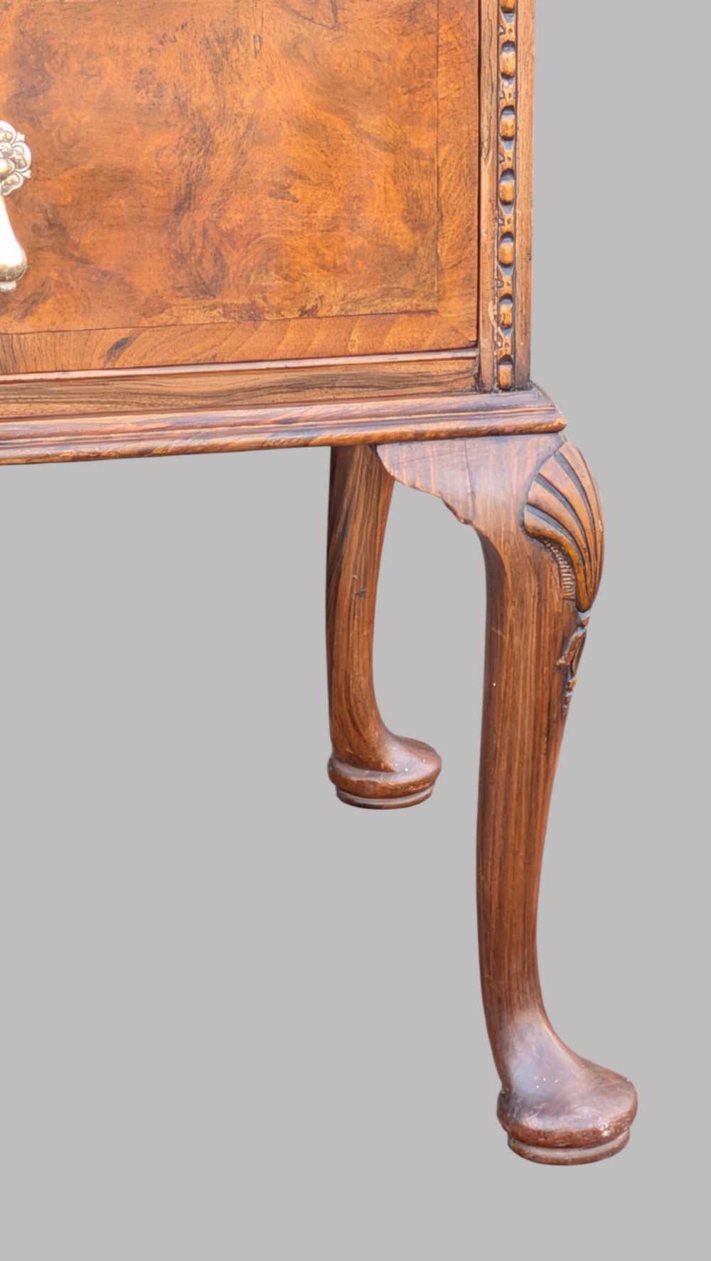 A Queen Anne style burr walnut chest of drawers featuring two short over two long drawers, brass drop handles, and carved cabriole legs. View IV
