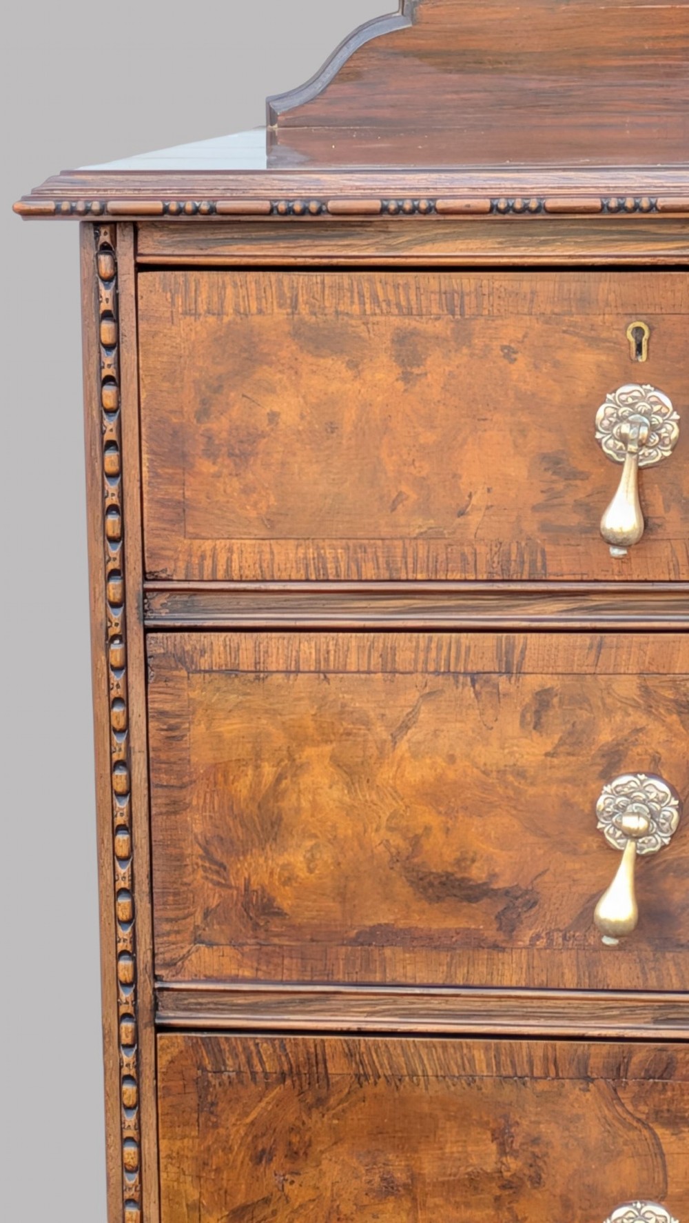 A Queen Anne style burr walnut chest of drawers featuring two short over two long drawers, brass drop handles, and carved cabriole legs. View VI