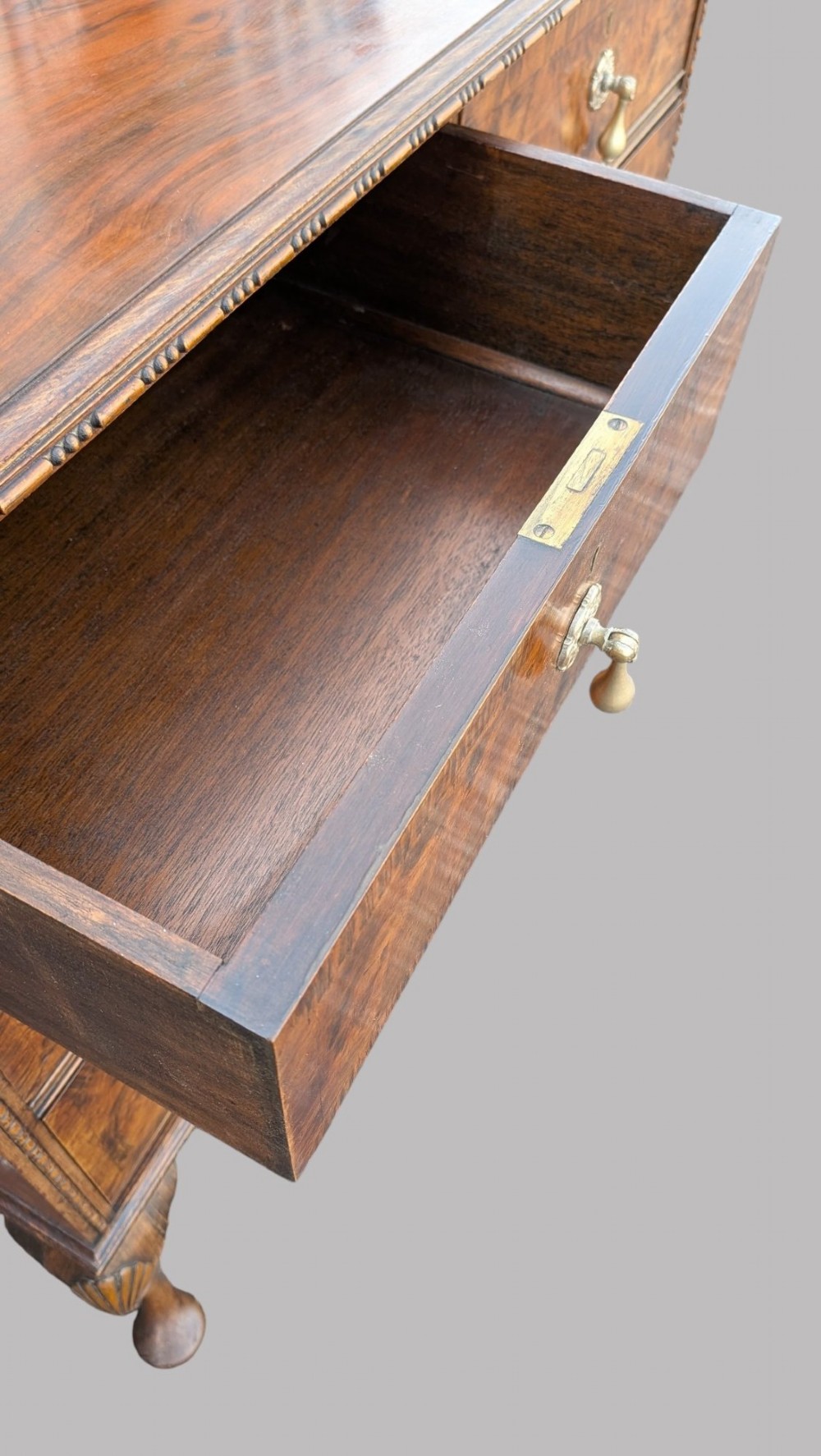 A Queen Anne style burr walnut chest of drawers featuring two short over two long drawers, brass drop handles, and carved cabriole legs. View X
