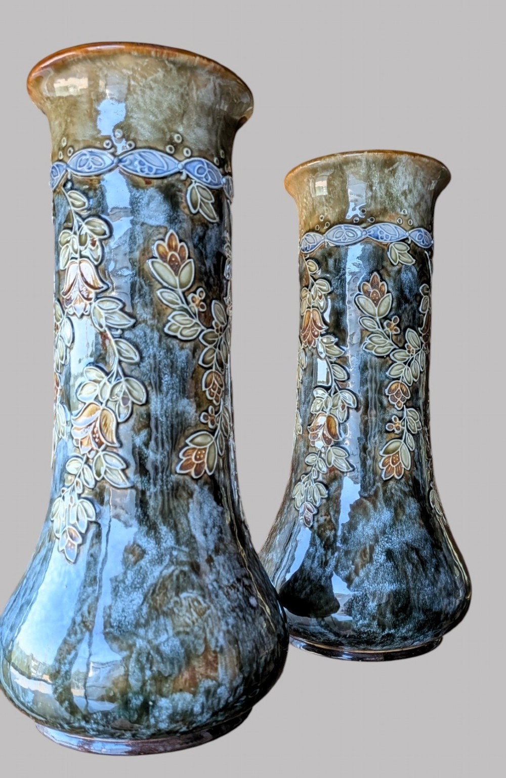 A matching pair of Art Nouveau stoneware vases featuring flared bases, mottled blue and brown glazes, and stylised floral relief decoration. View III