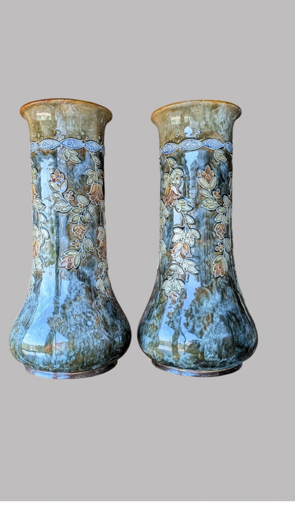 A matching pair of Art Nouveau stoneware vases featuring flared bases, mottled blue and brown glazes, and stylised floral relief decoration. View VI