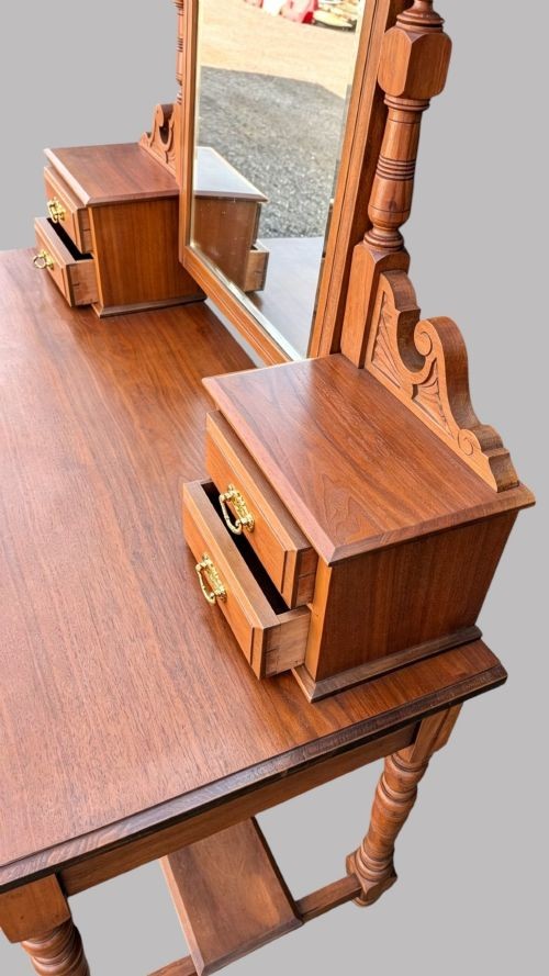 An Edwardian walnut dressing table with an upright swivelling mirror, carved pediment cresting, four drawers, turned legs, and brass hardware. View VI
