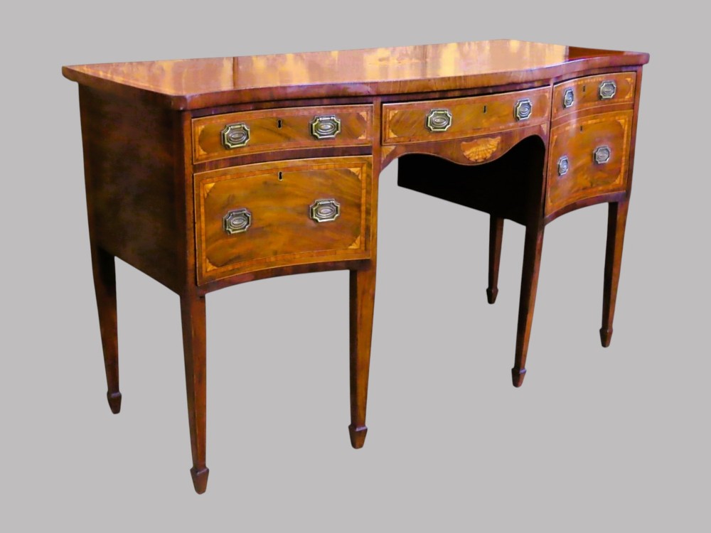 A Georgian serpentine-fronted mahogany sideboard with delicate boxwood inlay, brass drop handles, and square tapered legs.