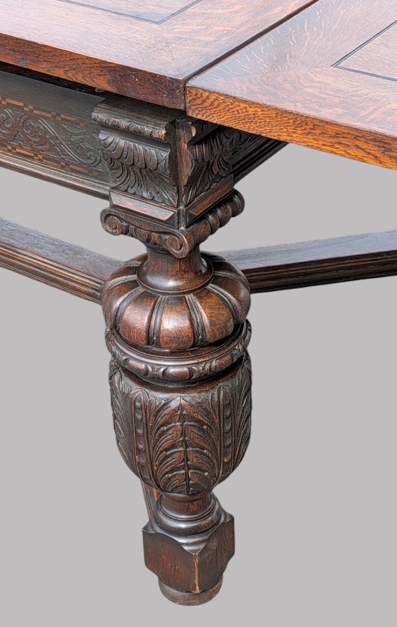 A rectangular extending oak dining table showing a quarter-sawn timber surface and carved bulbous legs underneath. View II