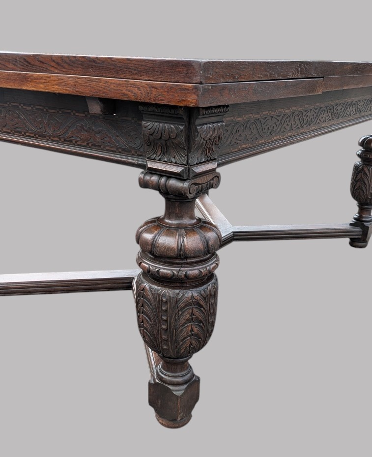 A rectangular extending oak dining table showing a quarter-sawn timber surface and carved bulbous legs underneath. View III