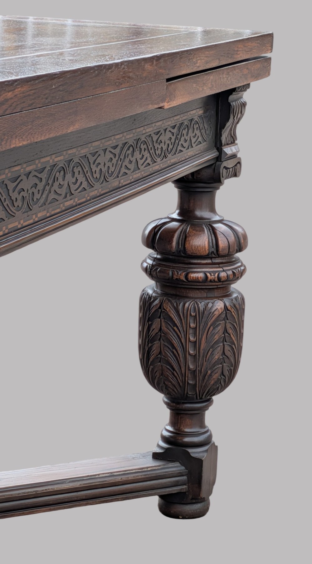 A rectangular extending oak dining table showing a quarter-sawn timber surface and carved bulbous legs underneath. View IV